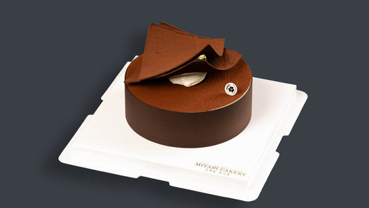 Miyabi Tiramisu Trilogy cake with cocoa-dusted chocolate decoration on a white cake board