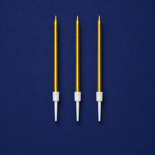 Set of three metallic gold cake candles with white holders on a blue background