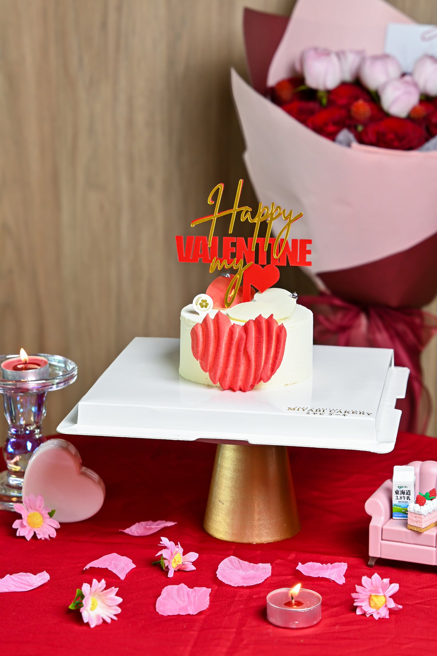 Valentine's Day-themed cake with heart design, flowers, and 'Happy Valentine' text on a red tablecloth.