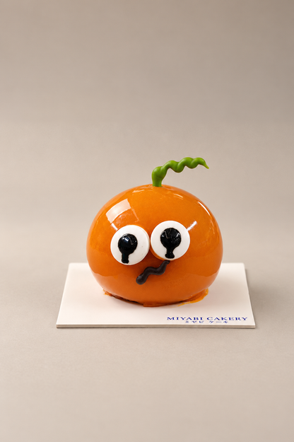 Trickster Caramel: orange pumpkin-shaped cake with eyes and a green stem. Non-alcoholic.